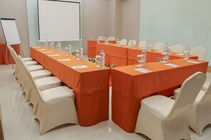Ein Konferenzraum mit einem langen Tisch, Stühlen und einer Projektionsleinwand.