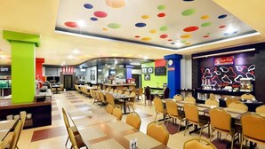 Un restaurante con varias mesas y sillas, una barra con un menú, y un diseño de techo colorido.