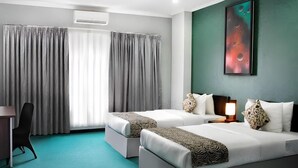 Habitación de hotel con dos camas, un escritorio y un ventanal con cortinas.