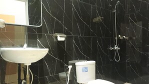 A modern bathroom with a black marble sink, toilet, and shower. - Grand Mansion Hotel (Blitar)