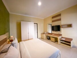 A hotel room with a large bed, a desk, a mirror, a wardrobe, and a television.