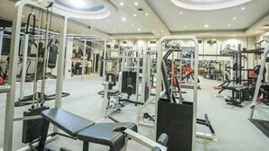 A gym with various exercise equipment, including weight machines and free weights. - Grand Mansion Hotel (Blitar)