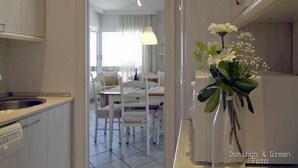Een moderne keuken met witte kasten en een eethoek met witte stoelen en een tafel.