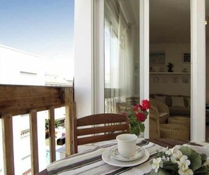A balcony with a table, chair, and a vase with flowers.
