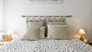 A bedroom with a bed, pillows, a headboard, a painting, and bedside lamps. - MARICEL Apartment - right on the beach (Calafell)