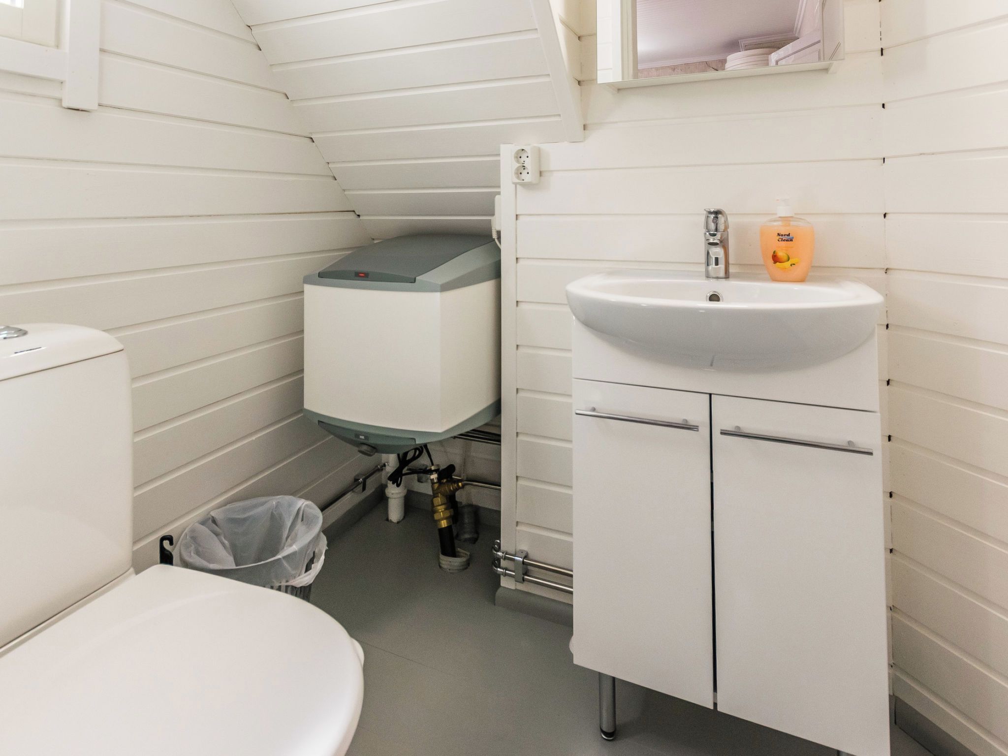 A compact bathroom with a toilet, a sink, and a toilet paper holder.