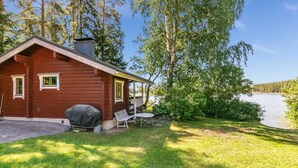 A cabin with a porch, a covered grill, and a small table and chair set. - Vacation home Elfvik by Interhome (Porvoo)