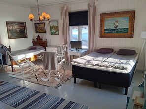 A bedroom with a bed, a desk, a rocking chair, and a window with curtains. - Vacation home Elfvik by Interhome (Porvoo)