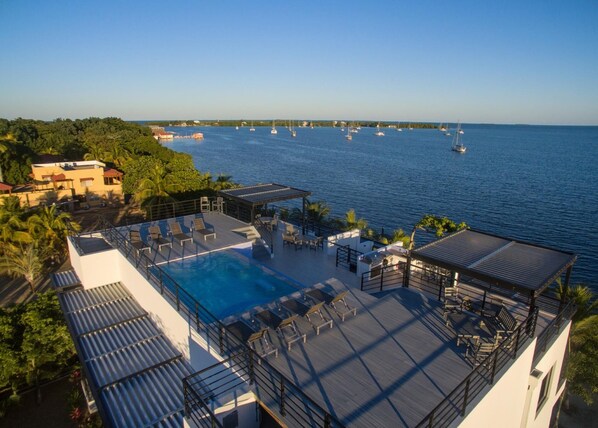 A rooftop pool area with lounge chairs and a view of the sea.