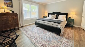 Une chambre à coucher avec un grand lit, une commode, une table de chevet, une lampe et un ventilateur de plafond.
