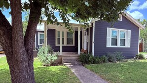 Une maison à deux étages avec un porche à l’avant, une boîte aux lettres et un petit jardin.