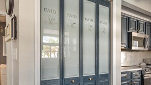 A kitchen with dark blue doors, white walls, and wooden flooring.