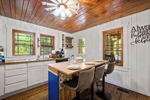 A kitchen with wooden cabinets, a central island, and a dining area with chairs.