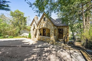Una casa de piedra con chimenea, puerta principal y un pequeño porche.
