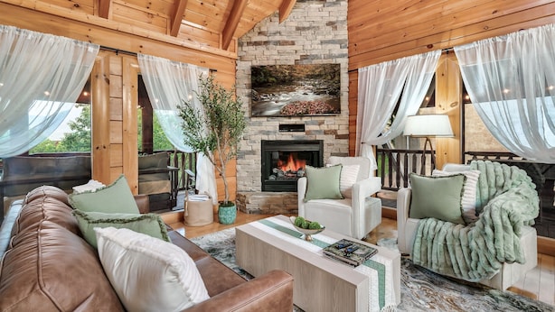 Ein gemütliches Wohnzimmer mit Kamin aus Stein, Ledersofas und einem großen Fernsehbildschirm.