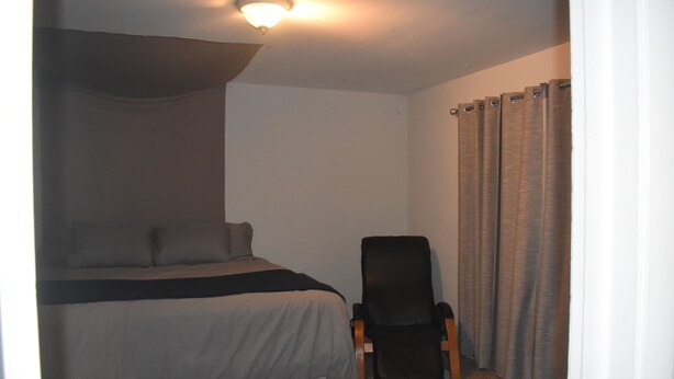 Une chambre à coucher avec un lit, une chaise et un rideau.