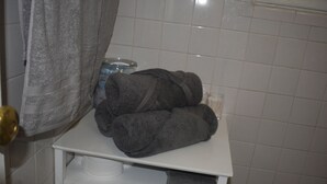 Une salle de bain avec un lavabo blanc, un porte-serviettes et un bocal en verre posé sur le comptoir.