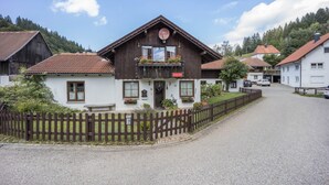 Un bâtiment de style chalet traditionnel, doté d’un balcon, d’une clôture en bois et surplombant un ciel dégagé.
