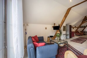 A living room with a sofa, a glass coffee table, a red rug, and a television.