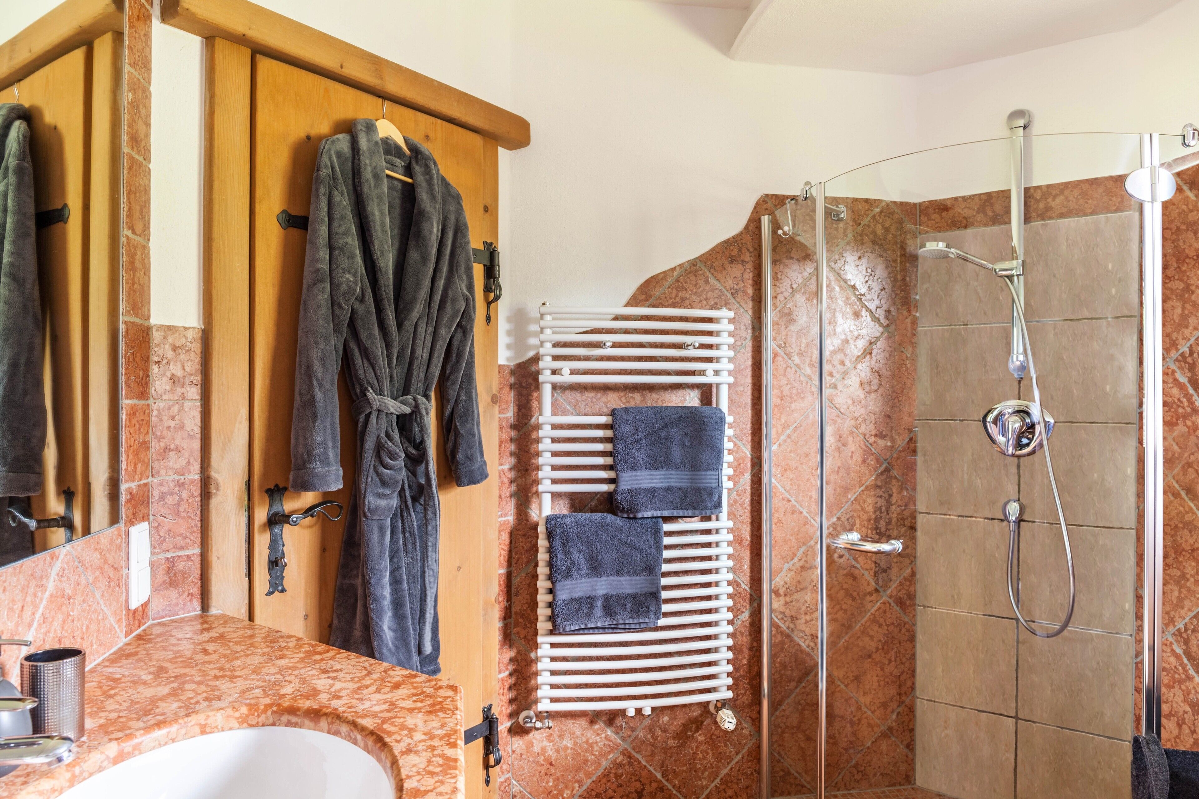 Een badkamer met een douche, een handdoekhouder en een spiegel.