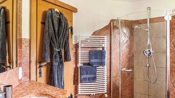 Een badkamer met een douche, een handdoekhouder en een spiegel.