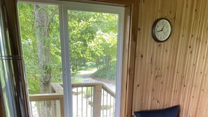 Una cabaña de madera con ventana, un reloj y un banco acolchado azul.