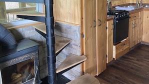 Una cocina rústica con armarios de madera, una estufa y un lavamanos.
