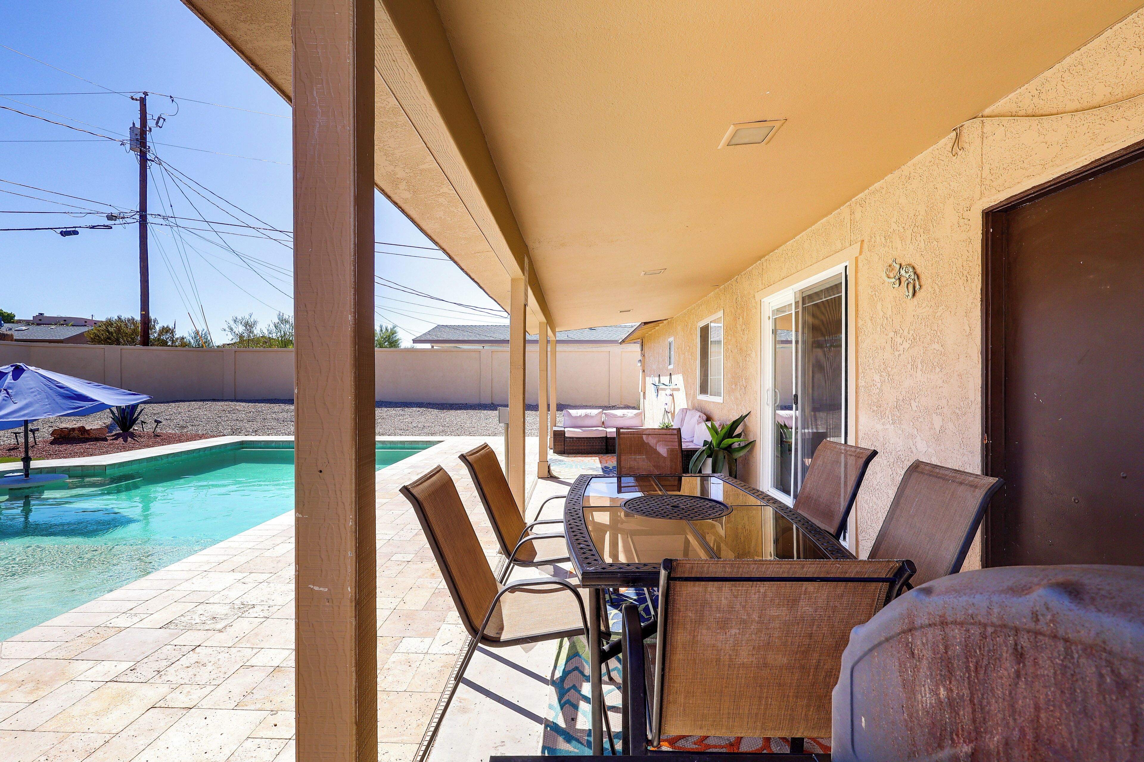 Un espacio de patio techado con piscina, mobiliario exterior y vistas del vecindario.