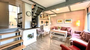 A modern living room with a staircase, a kitchen area, and a dining space.
