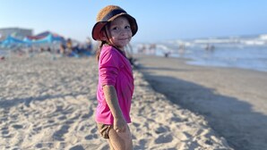 A child standing on a sandy beach with a clear sky in the background. - Luxurious 3 Story Townhome, private pool, Elevator, 3 minute walk to the beach!! (South Padre Island)