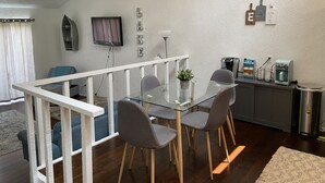 A modern kitchen with a glass dining table, grey chairs, a coffee machine, and a small potted plant. - Perfect Lake Escape (Holiday Island)