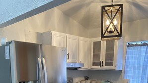 A modern kitchen with stainless steel appliances, white cabinetry, a patterned rug, and a hanging light fixture. - Perfect Lake Escape (Holiday Island)