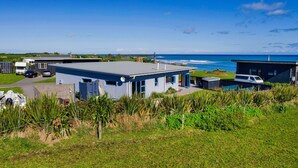 A modern house with a flat roof and a large balcony overlooking the ocean. - Coastal Daze - New Plymouth Holiday Home (New Plymouth)