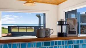 A kitchen counter with a coffee maker, a mug, and a bag of coffee beans. - Coastal Daze - New Plymouth Holiday Home (New Plymouth)