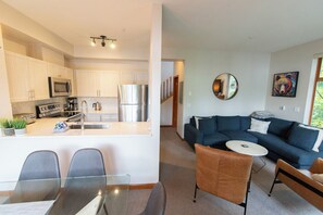 A modern kitchen with stainless steel appliances and a dining area with a glass table.