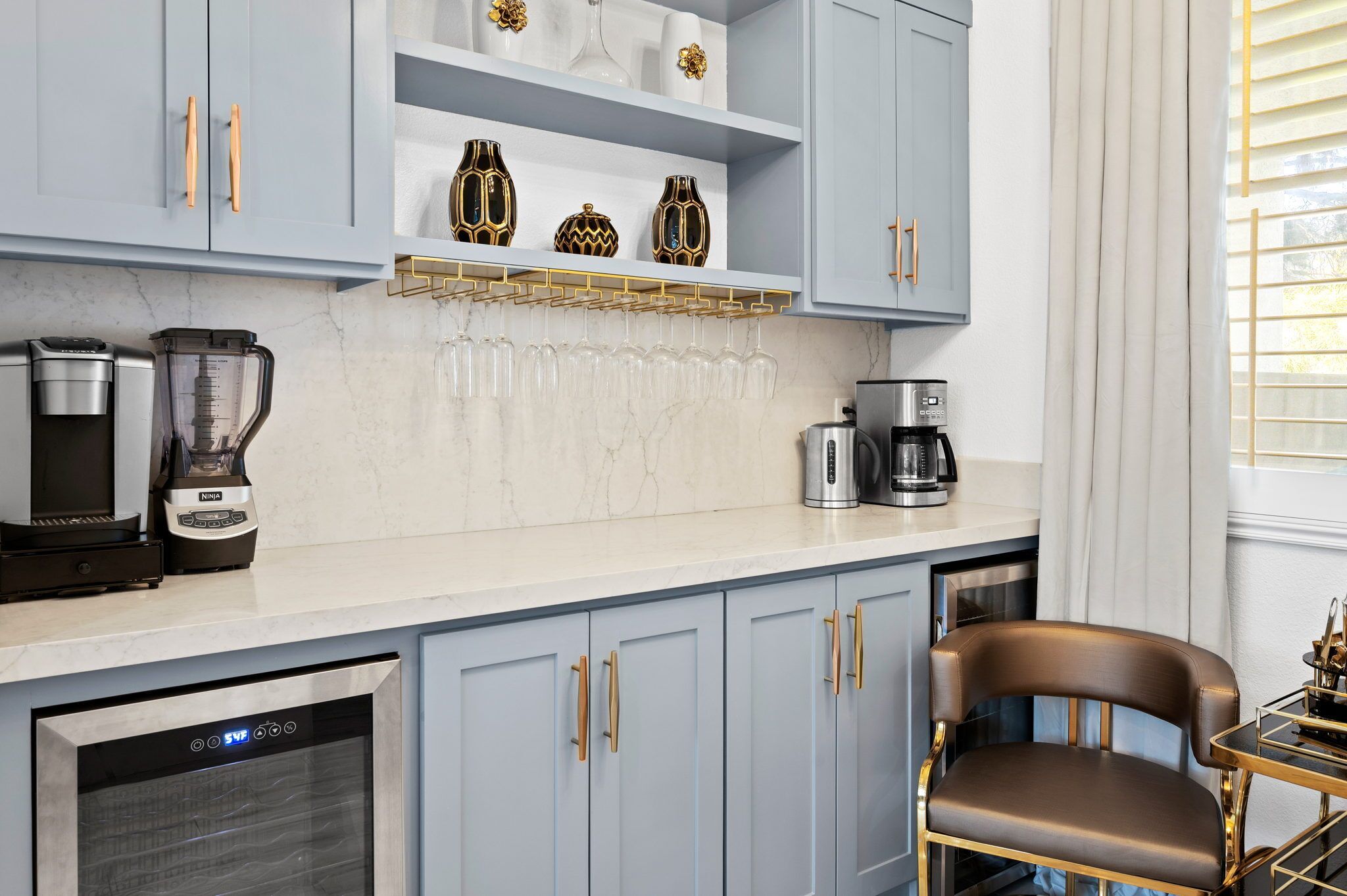 A modern kitchen with light blue cabinets, a coffee maker, a blender, and a dishwasher.