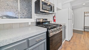 A kitchen with a stainless steel stove, microwave, and refrigerator. - Vanderhut Chalet - Smart TV, BBQ, Fenced Yard (Sugarloaf)