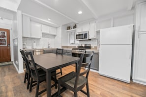 A modern kitchen with white cabinets, a central island, a microwave, stove, and a refrigerator.