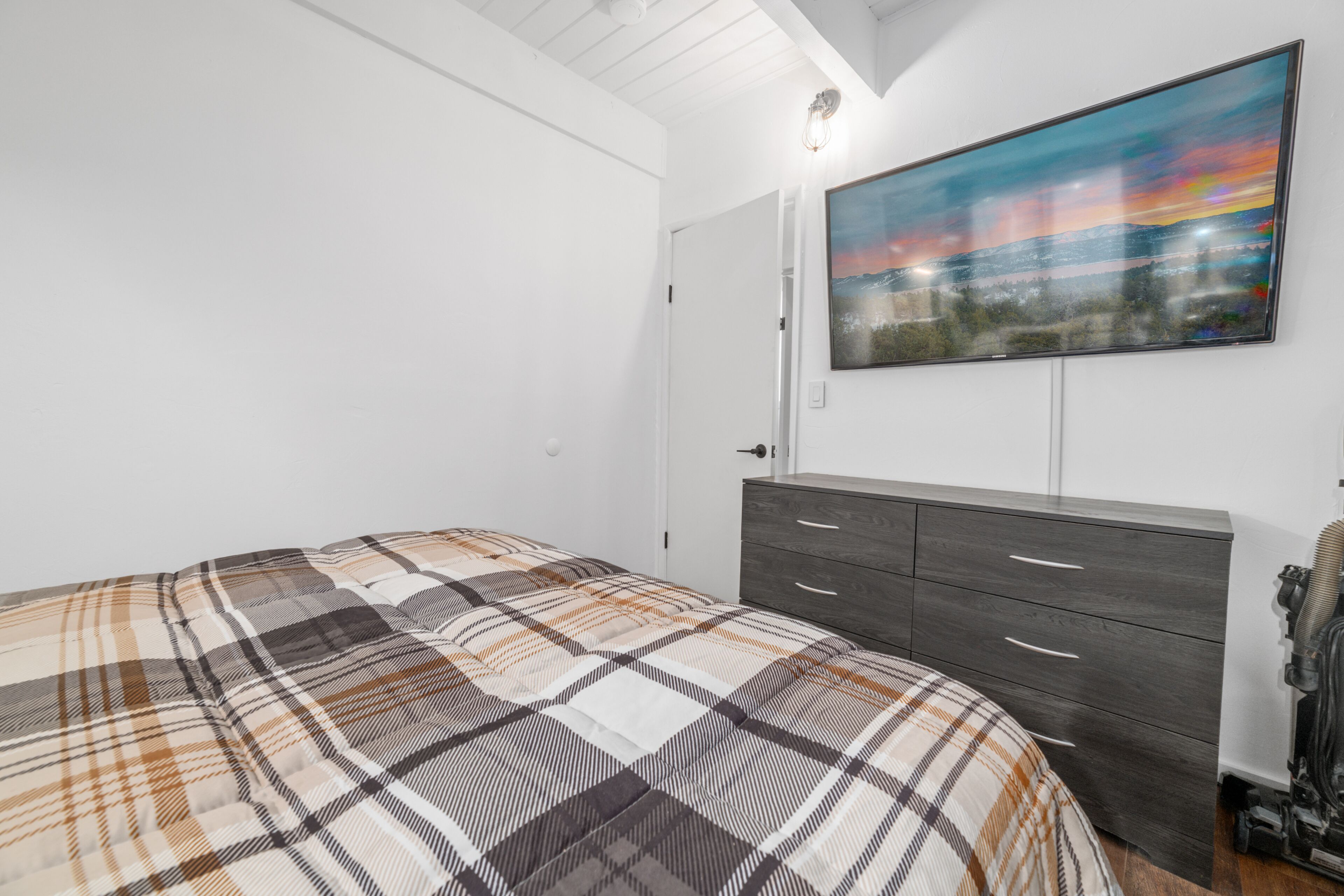 A bedroom with a bed, a dresser, and a painting on the wall.
