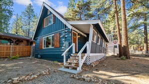 A two-story wooden cabin with a porch and a small deck, surrounded by trees. - Vanderhut Chalet - Smart TV, BBQ, Fenced Yard (Sugarloaf)
