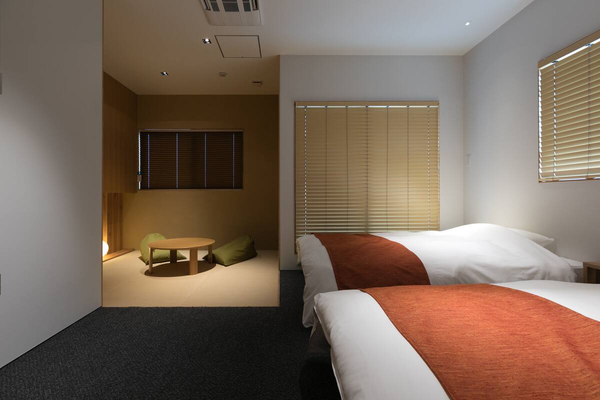 Ein Hotelzimmer mit zwei Betten, einem kleinen runden Tisch und einem Sofa.
