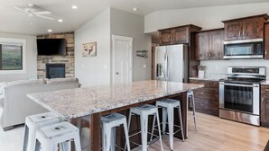Una cocina moderna con encimeras de granito, electrodomésticos de acero inoxidable y armarios de madera.