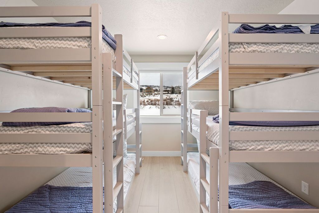Een slaapkamer met stapelbedden en uitzicht op een besneeerd landschap.