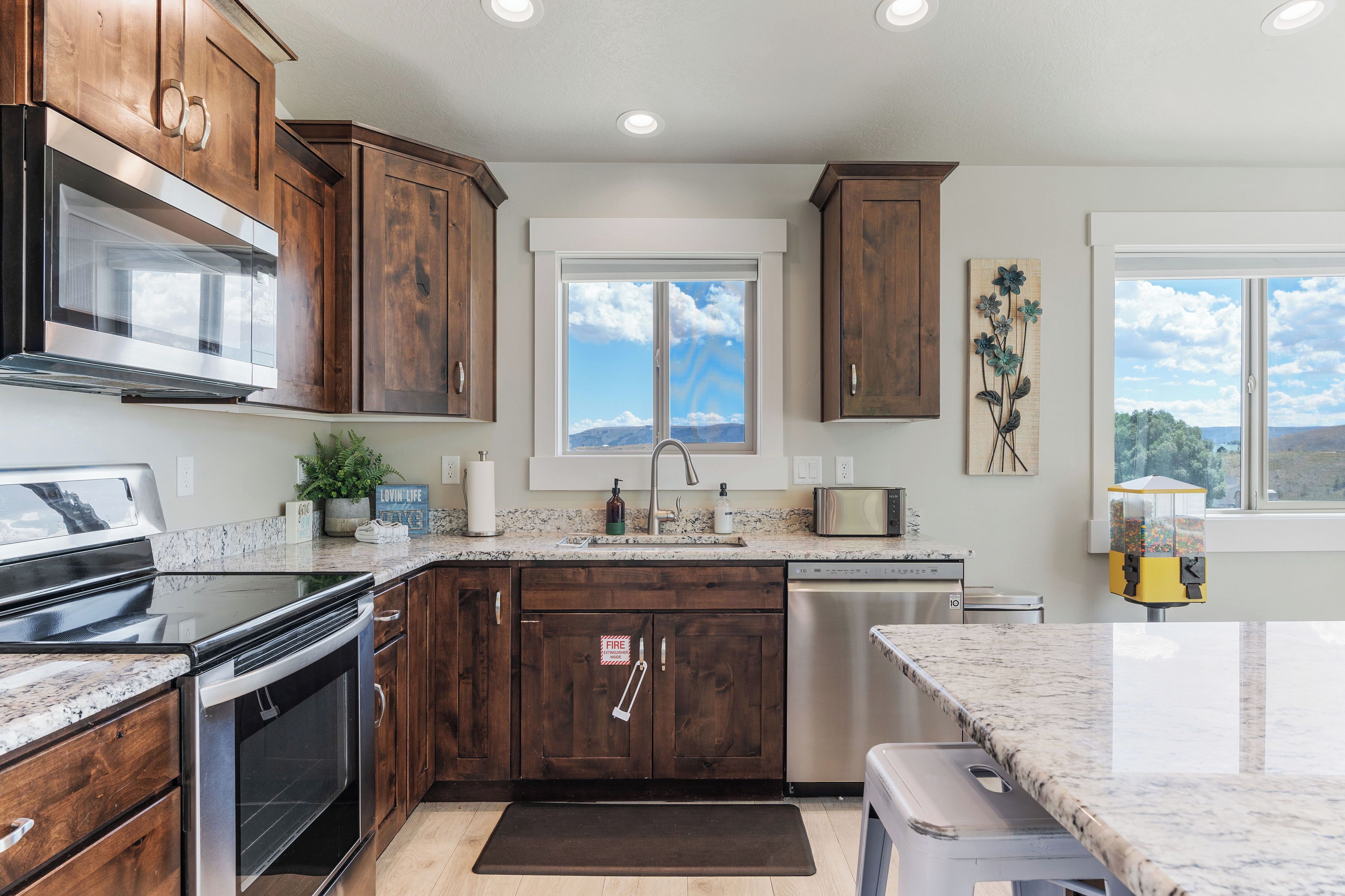 A kitchen with wooden cabinets, stainless steel appliances, a window with a view, and a marble countertop.
