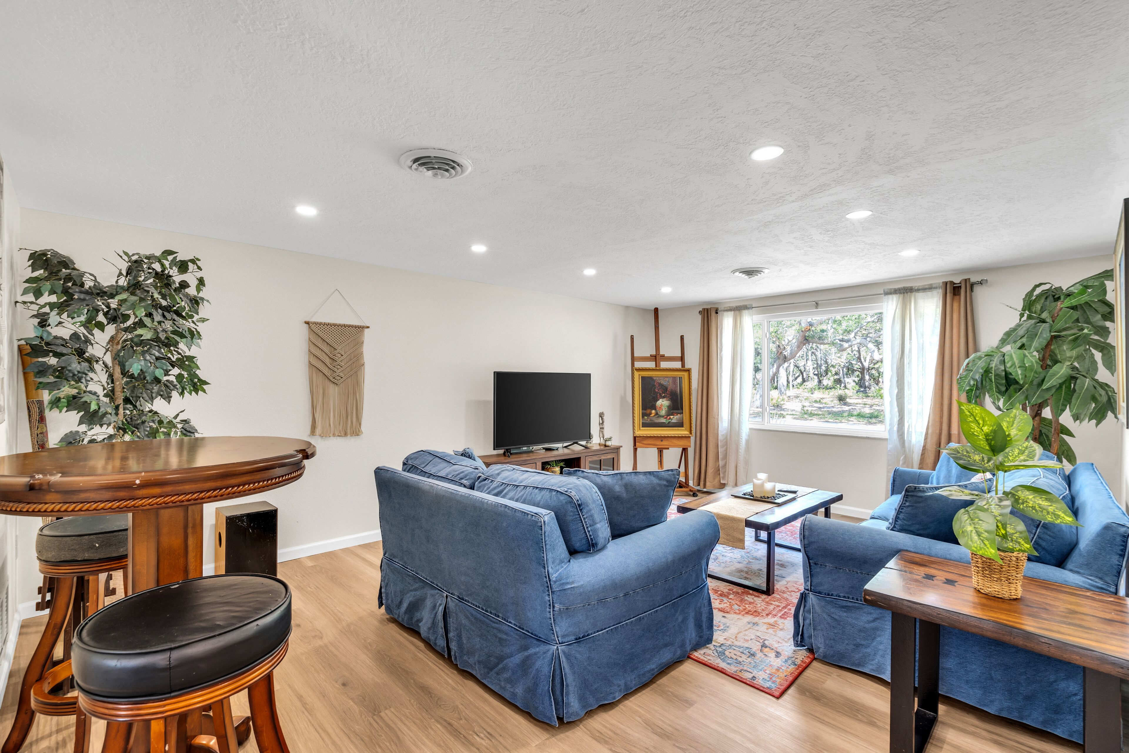 A living room with a sofa, a coffee table, a TV, and a dining area with a table and chairs.