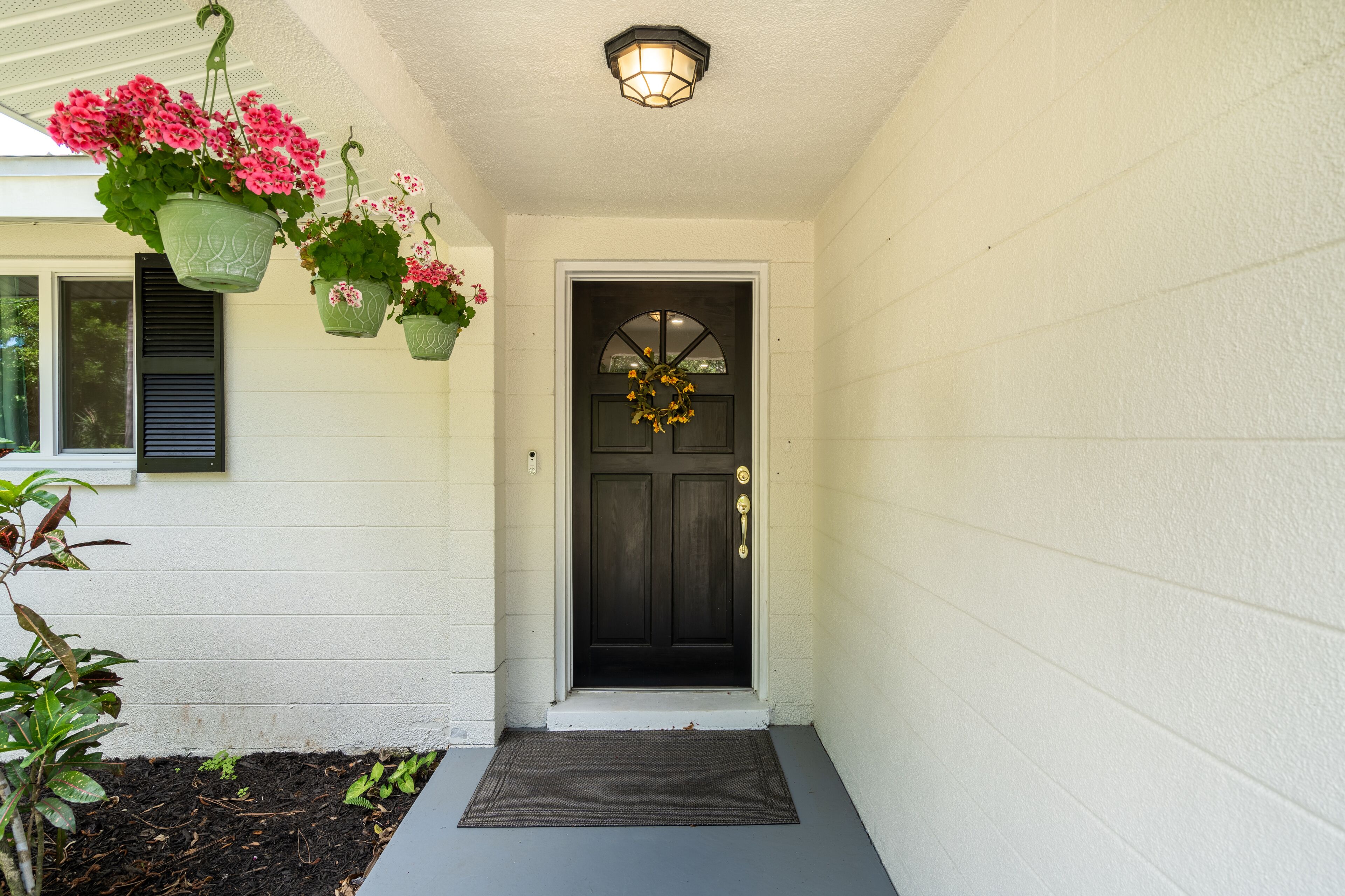 A front door with a black door and a white wall.