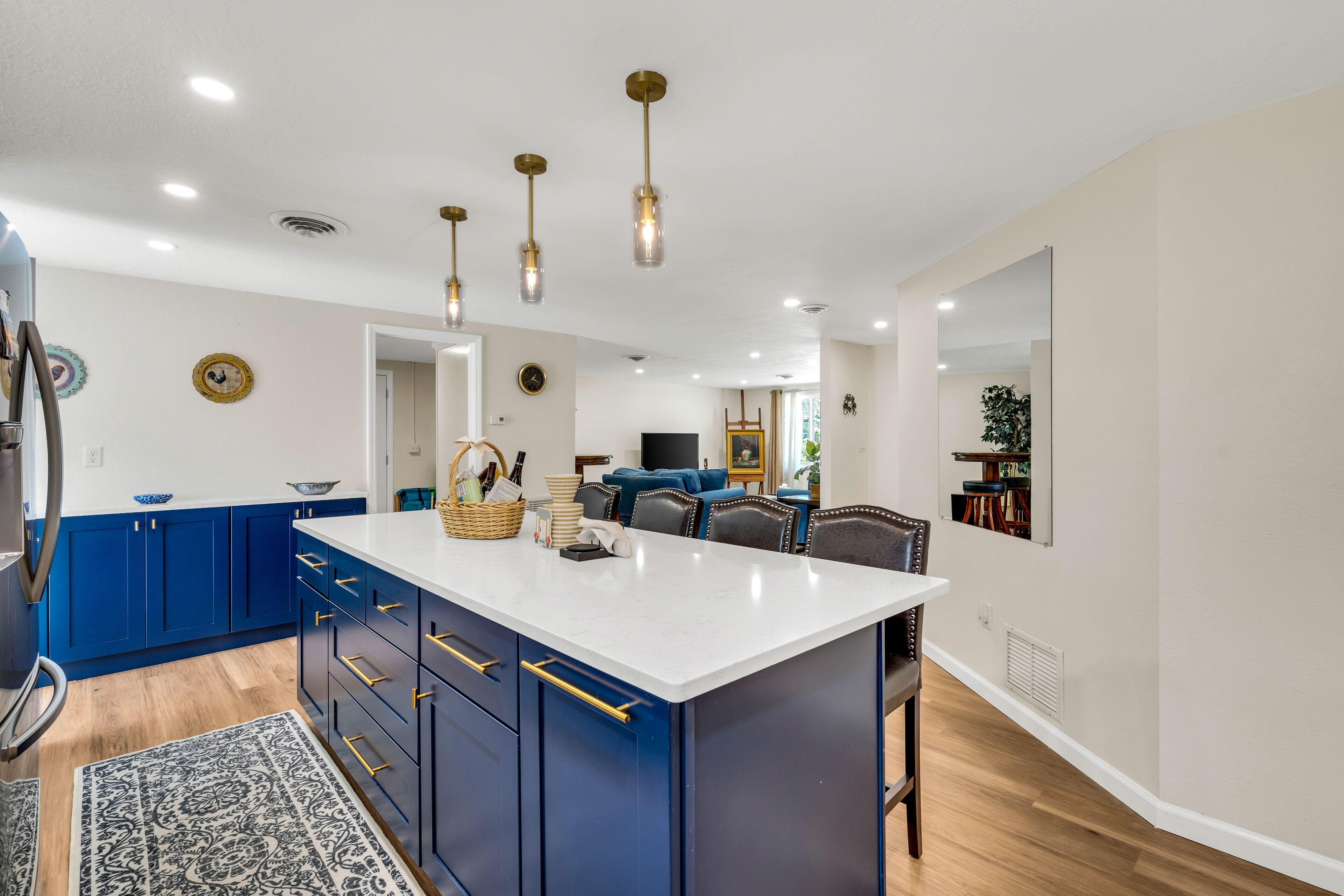 A modern kitchen with blue cabinets, a white island, and pendant lighting.