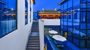 Un edificio moderno con arquitectura china tradicional, una escalera que lleva al segundo piso y un área de estar al aire libre con sombrillas.