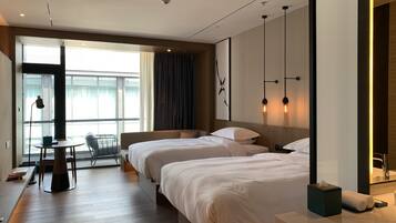 A modern hotel room with two beds, a desk, and a chair.