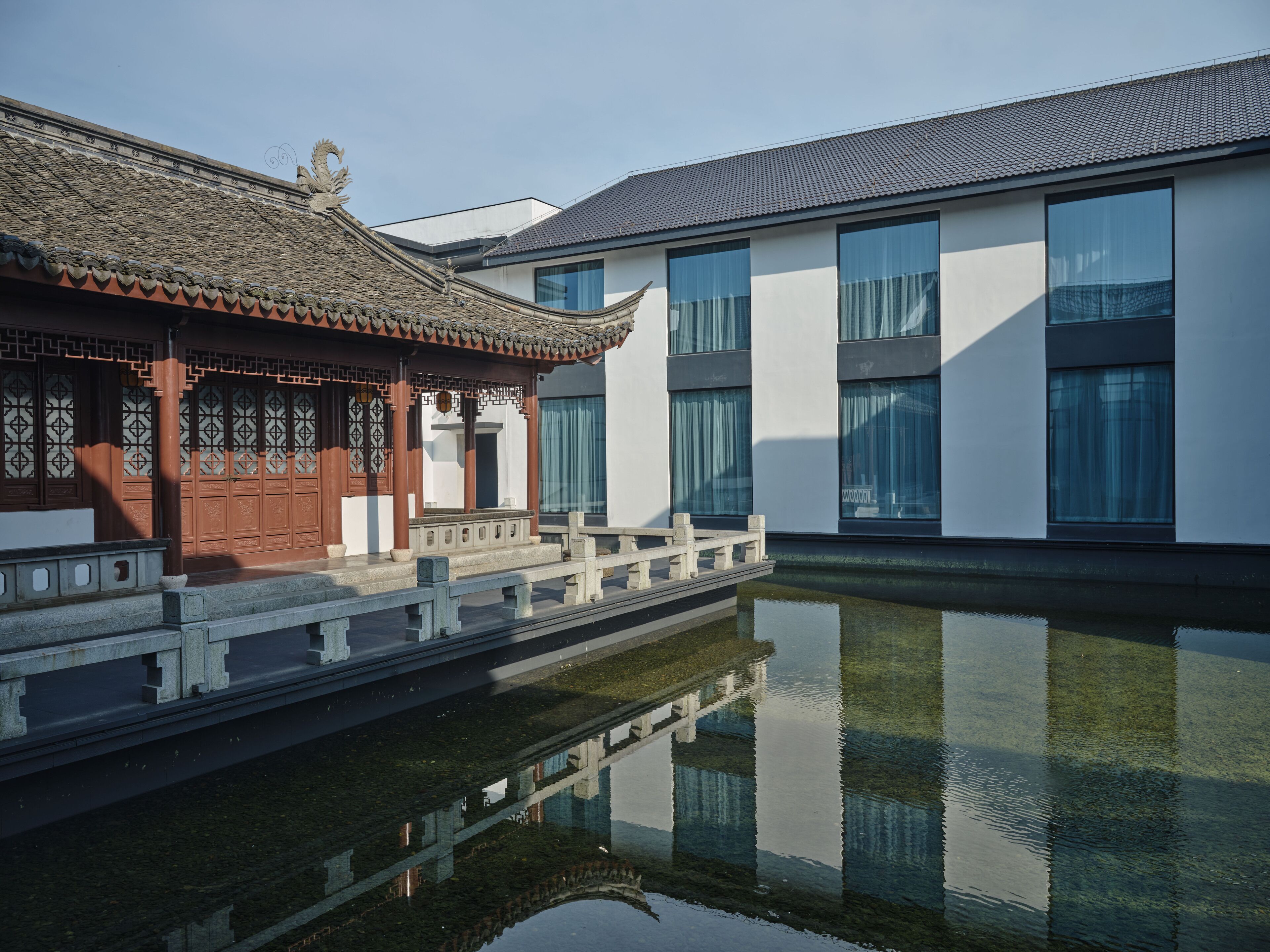 A traditional building with a tiled roof and a modern structure with large windows.